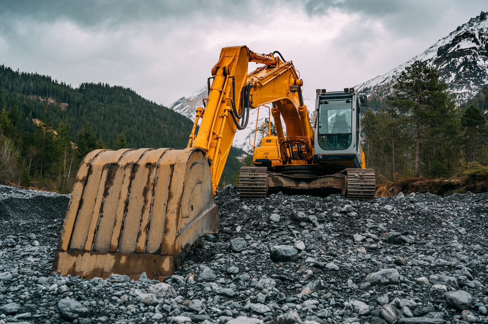 yellow and black excavator on rocky ground